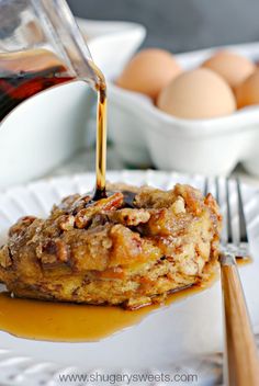 someone pouring syrup on some food on a plate