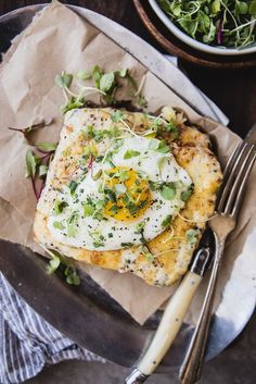 an egg is on top of a piece of bread with herbs and other toppings