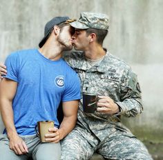 two men in uniform kissing each other while holding coffee cups and talking to each other