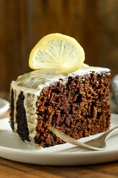 a piece of cake on a plate with a fork and lemon wedged in it