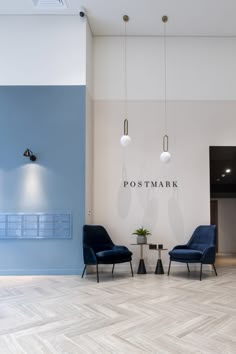 two blue chairs sitting in front of a postmark logo on the wall next to a table