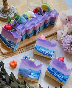 three pieces of soap sitting on top of a cutting board next to flowers and fruit