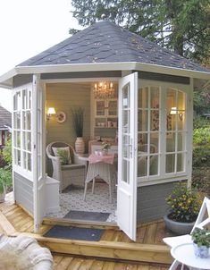 a gazebo sitting on top of a wooden deck next to a table and chairs