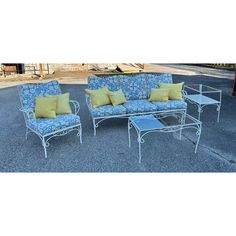 four piece patio furniture set with blue and yellow pillows on the cushions, sitting in a parking lot