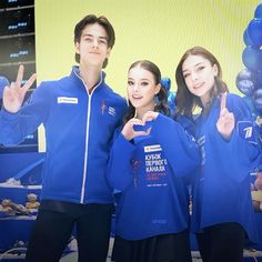 three people in blue jackets standing next to each other with their hands up and one person making the peace sign