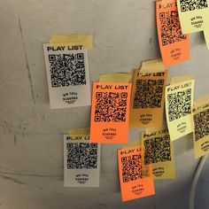 several pieces of yellow paper with qr - code stickers on them hanging from the ceiling