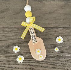 a wooden spoon hanging from a string with daisies around it