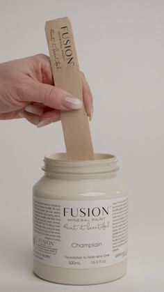 a person is holding a wooden stick in a jar with some cream on the top