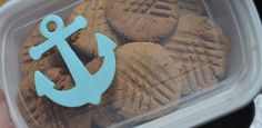 a plastic container filled with cookies decorated like an anchor