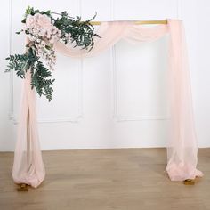 a pink wedding arch with flowers and greenery on the top is ready for guests to arrive