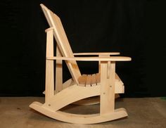 a wooden rocking chair sitting in front of a black background with the seat up and one leg down