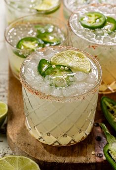 three margaritas with lime and jalapenos garnish on a cutting board