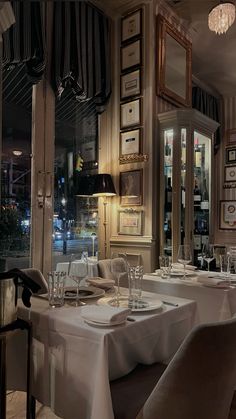 an empty restaurant with white table cloths and silverware on the dining room tables