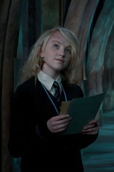 a woman in a harry potter costume holding a piece of paper and looking at the camera