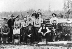 an old black and white photo of men posing for a group photograph in the woods