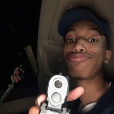 a man is holding up a camera in the back seat of a car at night