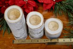 three wooden logs sitting on top of a table next to a measuring tape and poinsettis