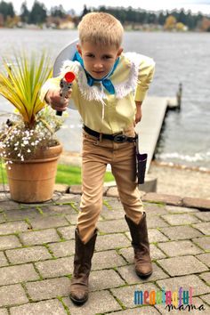 a young boy dressed in costume standing next to a body of water and holding a knife