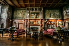 an old fashioned living room with wood paneling and paintings on the walls, along with red couches