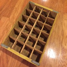 a wooden box filled with lots of compartments on top of a hard wood floor next to a wall