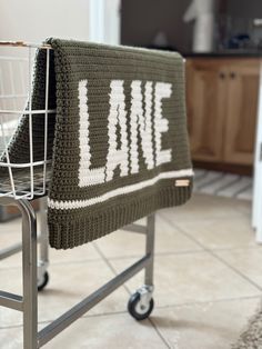 a crocheted blanket sitting on top of a metal chair in a kitchen next to a basket