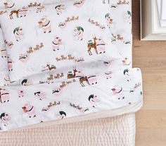 a bed covered in white sheets with deer and snowflakes on them