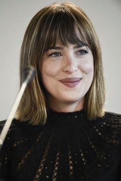 a woman holding an umbrella in front of her face and looking at the camera with a smile on her face