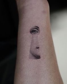 a woman's face with an eye tattoo on her arm