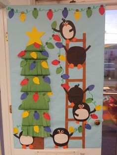 a bulletin board with penguins and a christmas tree on the bottom, hanging from a ladder