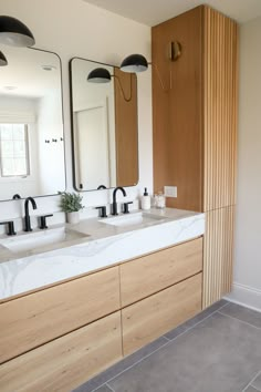 a bathroom with two sinks, mirrors and lights on the wall above them is shown