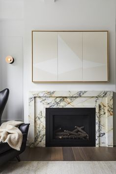 a living room with marble fireplace and black chair