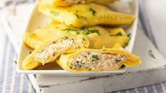 some stuffed shells are on a white plate with blue and white table cloth next to it