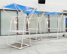 three white chairs with blue umbrellas on them