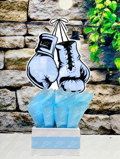 a paper cutout of two boxing gloves sitting on top of an ice block in front of a stone wall