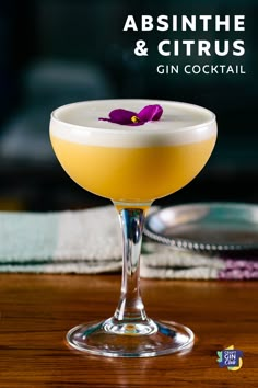 the absinthe and citrus gin cocktail is garnished with a purple flower