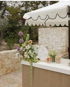 an outdoor bar with flowers and candles on the counter next to it, near a stone wall