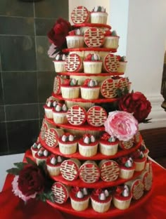 a red and white wedding cake with cupcakes on it