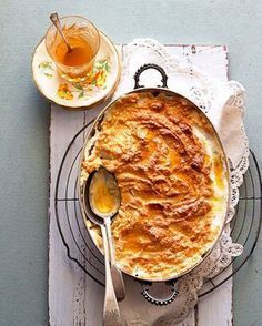 a pot pie on a plate next to a glass of orange juice and spoons