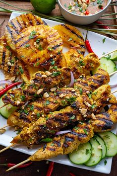 grilled chicken and vegetables on a white plate with chopsticks next to it