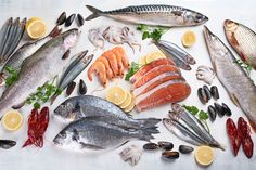 fish and seafood are arranged on a white surface