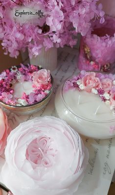 pink and white flowers are in vases on a table with other items around them