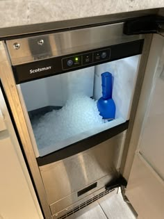 an ice machine is shown with blue containers in the freezer door, and it's light on