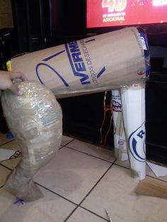 a person is holding a plastic bag over a trash can on the floor in front of a television