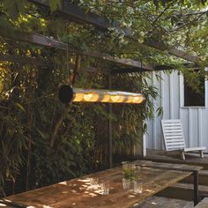 a wooden table sitting under a tree next to a white building with lights on it