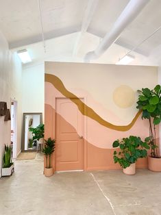 a room with potted plants on the floor and a painted wall in the background