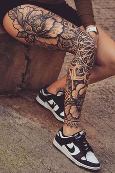 a woman sitting on top of a stone wall with tattoos on her legs and leg