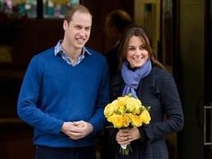 a man and woman standing next to each other in front of a door holding flowers