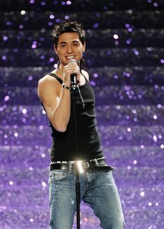 a man standing on top of a stage holding a microphone in his hand and singing