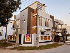 a two story house with multiple windows and lights on the front, in an urban setting