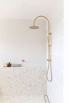 a white bathroom with a shower head and hand held shower faucet in it